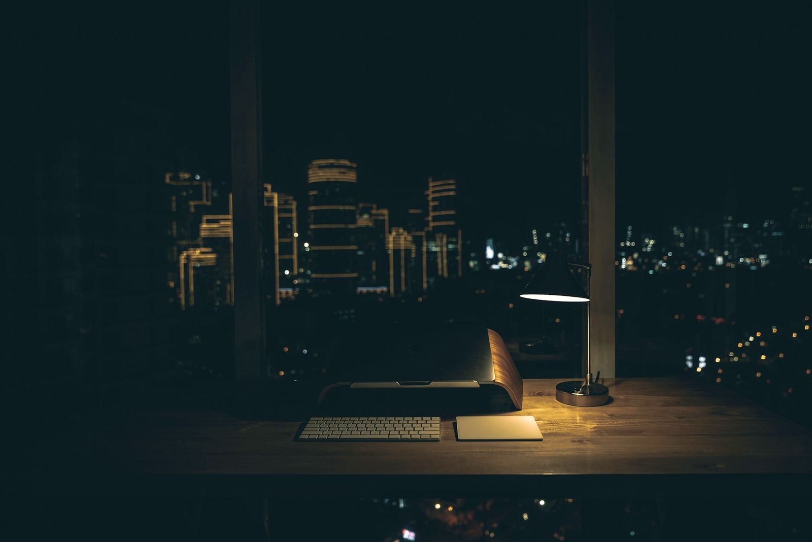 Mesa de trabalho iluminada à noite, com a cidade ao fundo